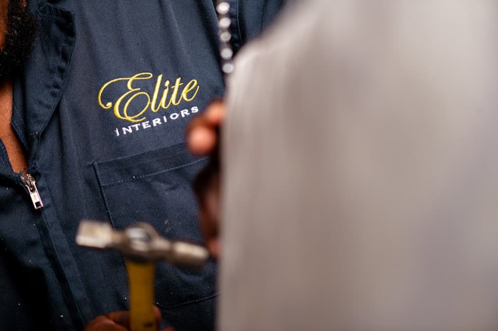 Elite Interiors logo embroidery on workwear — detail of craft in progress.