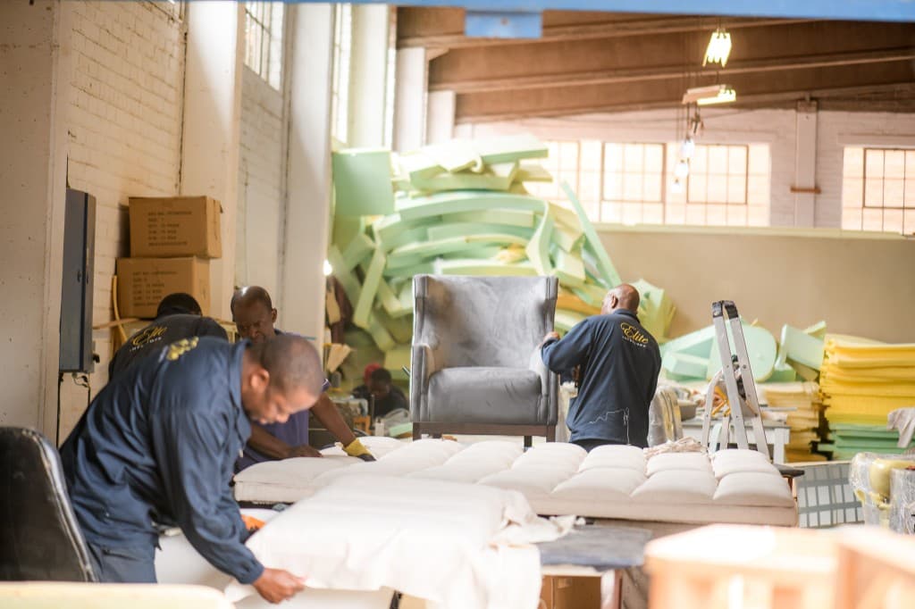Workshop floor — several makers at work on upholstered pieces.